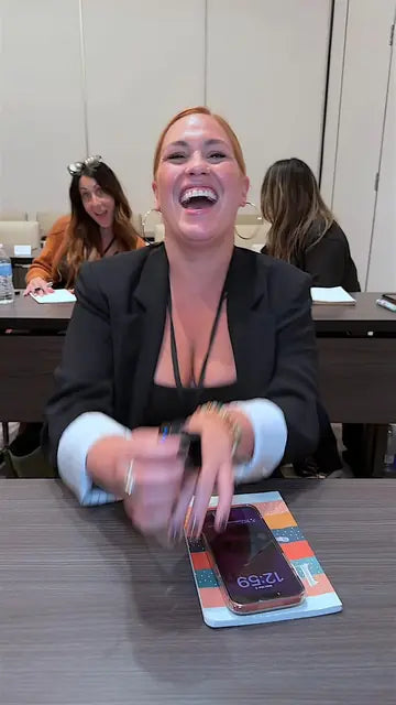 An attendee in a black blazer laughs out loud at her table during a session